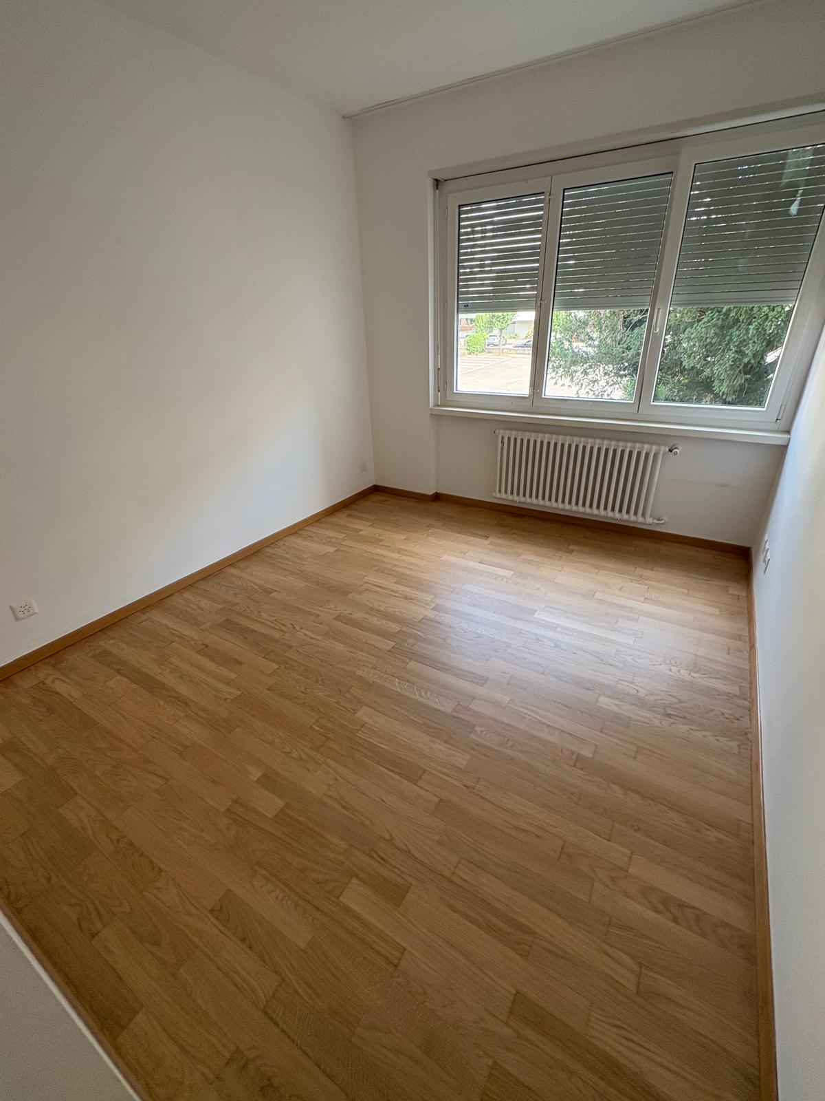 Second bedroom with large window and parquet flooring